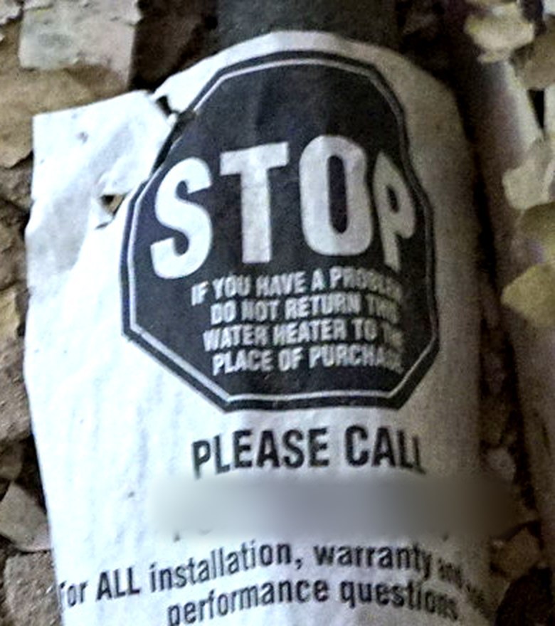 Bright hang tag on a water heater reading STOP, if you have a problem please call, do not return this water heater to the store