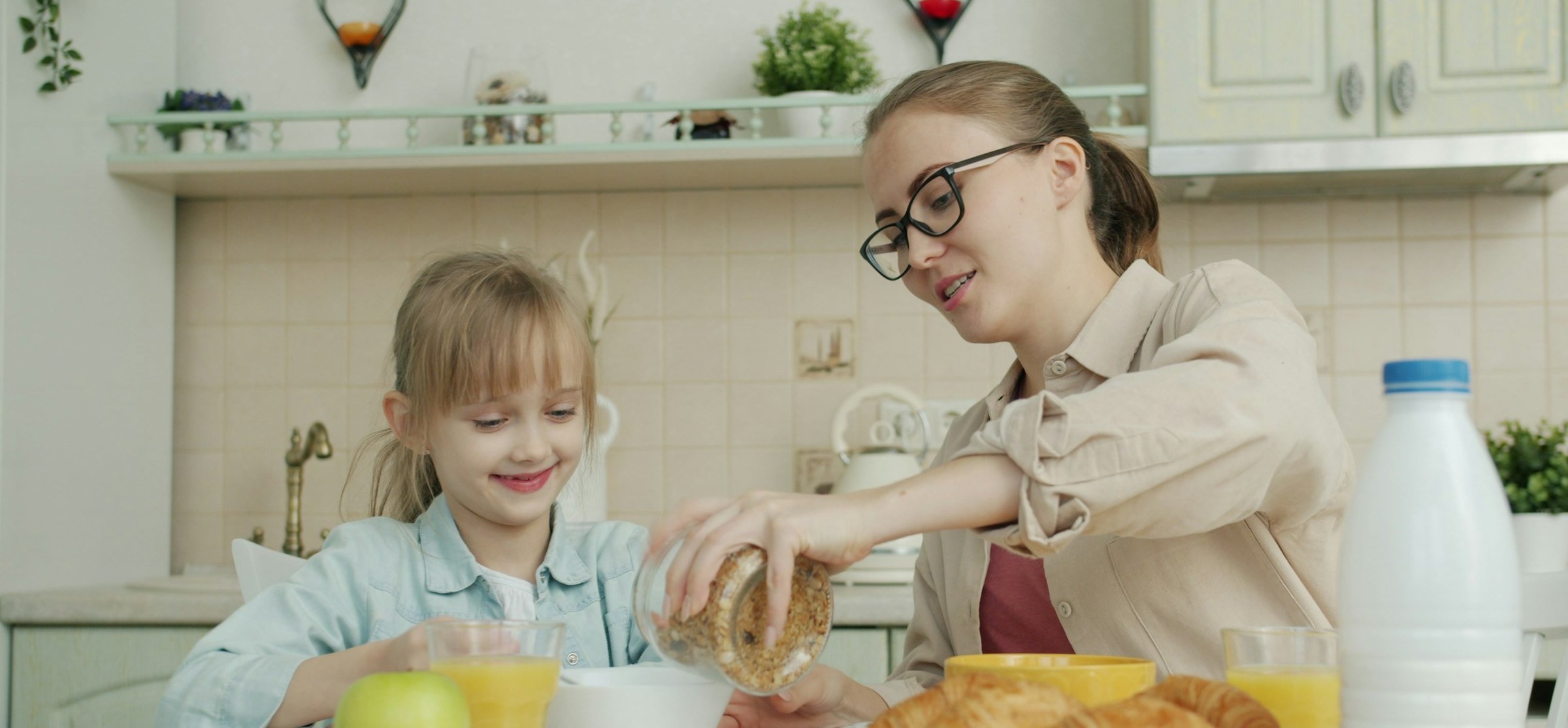 A mother and daughter enjoying breakfast at a bright kitchen table